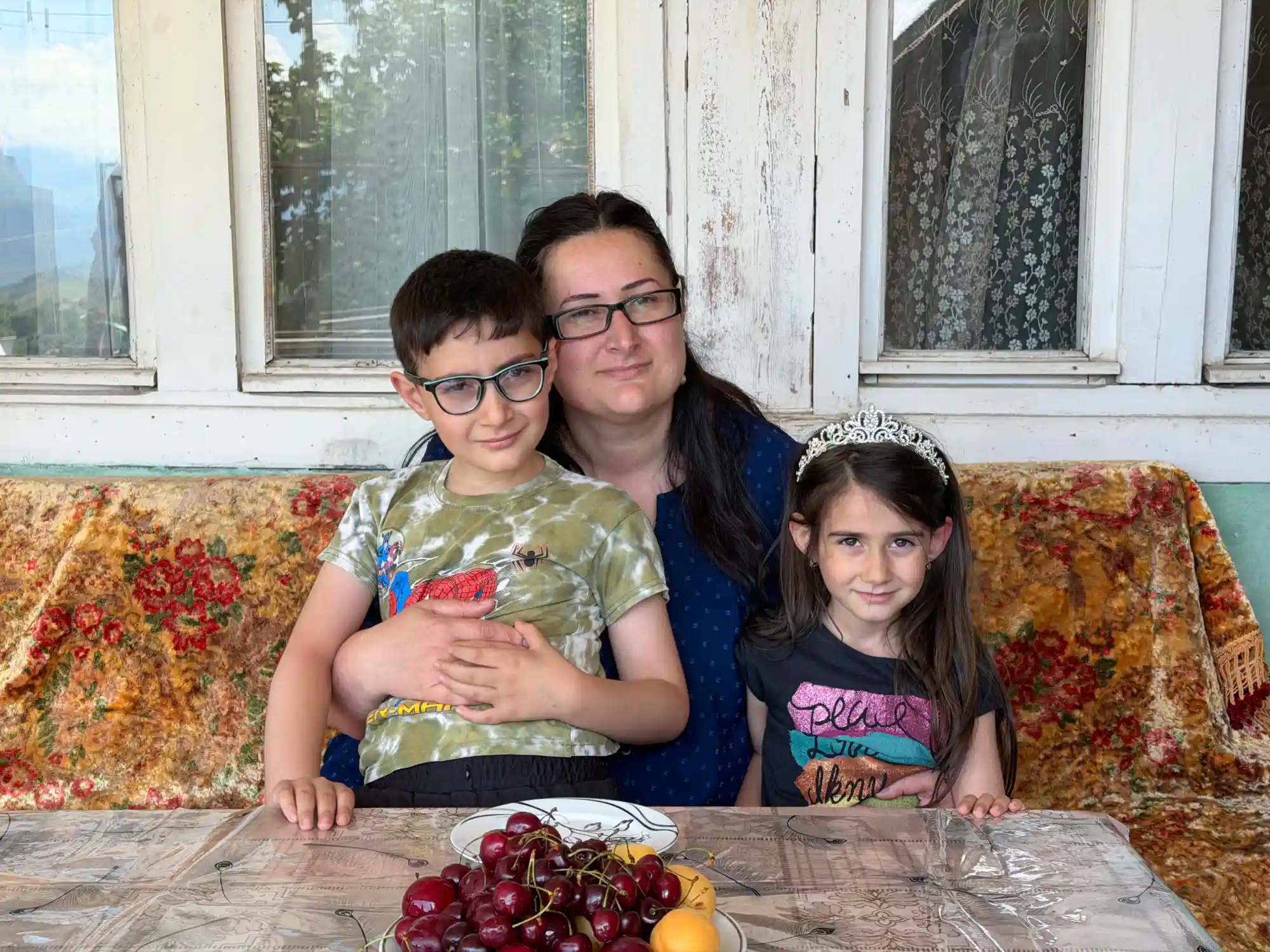 Refugee woman entrepreneur with her two children at home in the Lori region of Armenia