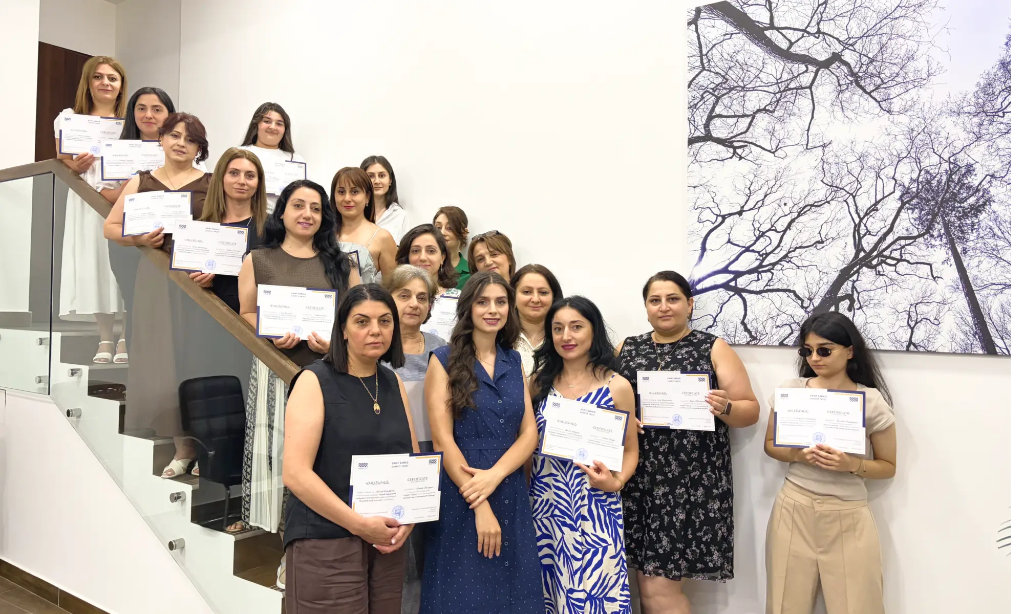 English for the Workplace graduates holding their certificates on a staircase in Yerevan, Armenia